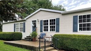 A single-story house with a front porch, a small staircase, and a well-maintained lawn.