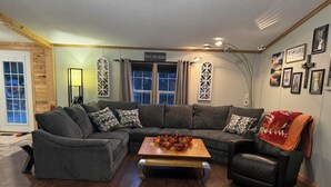 A living room with a sectional sofa, a coffee table, and a fireplace.