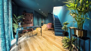 Un interior moderno con piso de madera, una escalera y diversas plantas en macetas.