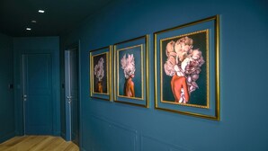 Un pasillo con paredes azules y suelo de madera, con tres obras de arte enmarcadas en la pared.