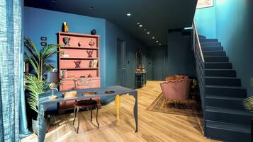 Un intérieur moderne comprenant un escalier, un coin repas avec une table et des chaises, et une bibliothèque agrémentée d’objets décoratifs.