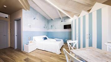 Un dormitorio con cama, mesitas de noche, televisor y paredes a rayas.