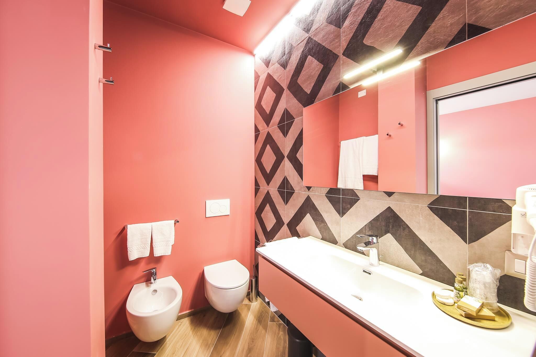 Ein Badezimmer mit rosa Wänden, einem weißen Waschbecken und einem Bidet.