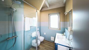 A bathroom with a glass-enclosed shower, a toilet, and a sink with a hairdryer.