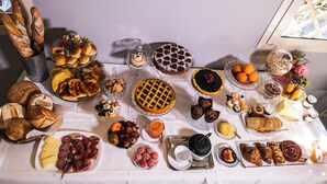 Una mesa con diversos alimentos, incluyendo panes, pasteles, frutas y quesos.