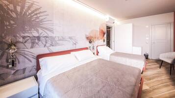 A hotel room with two beds, a nightstand, a lamp, a wall with a leaf pattern, and a door.