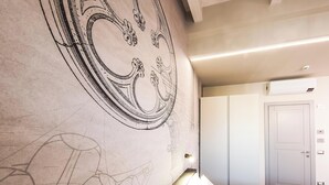 Habitación de hotel con un amplio mural decorativo, una cama, un armario y una puerta con interruptor de luz.