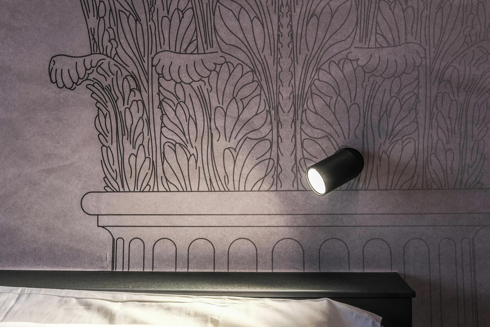 A wall with a detailed floral pattern and a modern light fixture.