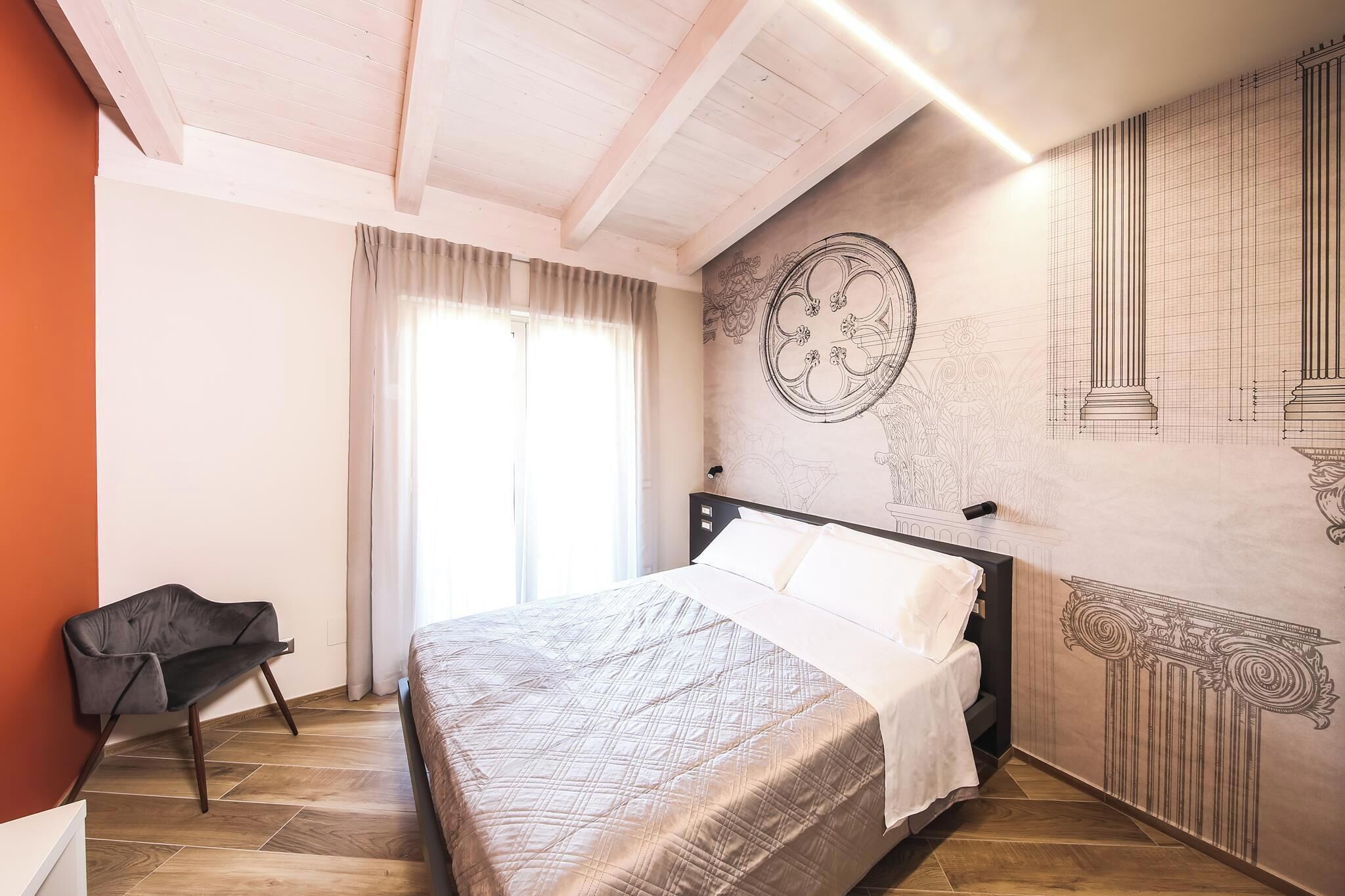 Een slaapkamer met een bed, een stoel en een muur met architectuurtekeningen.