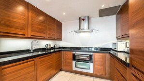 A modern kitchen with wooden cabinets, a stainless steel range hood, and built-in appliances. - Spacious 2 bed in Pimlico (London)