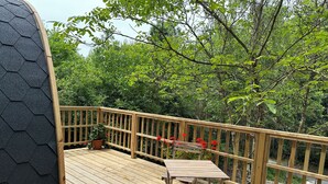 A wooden deck with a table and chairs, surrounded by a wooden railing and potted plants. - Logement Insolite Cabane Pod sur Pilotis (Valencisse)