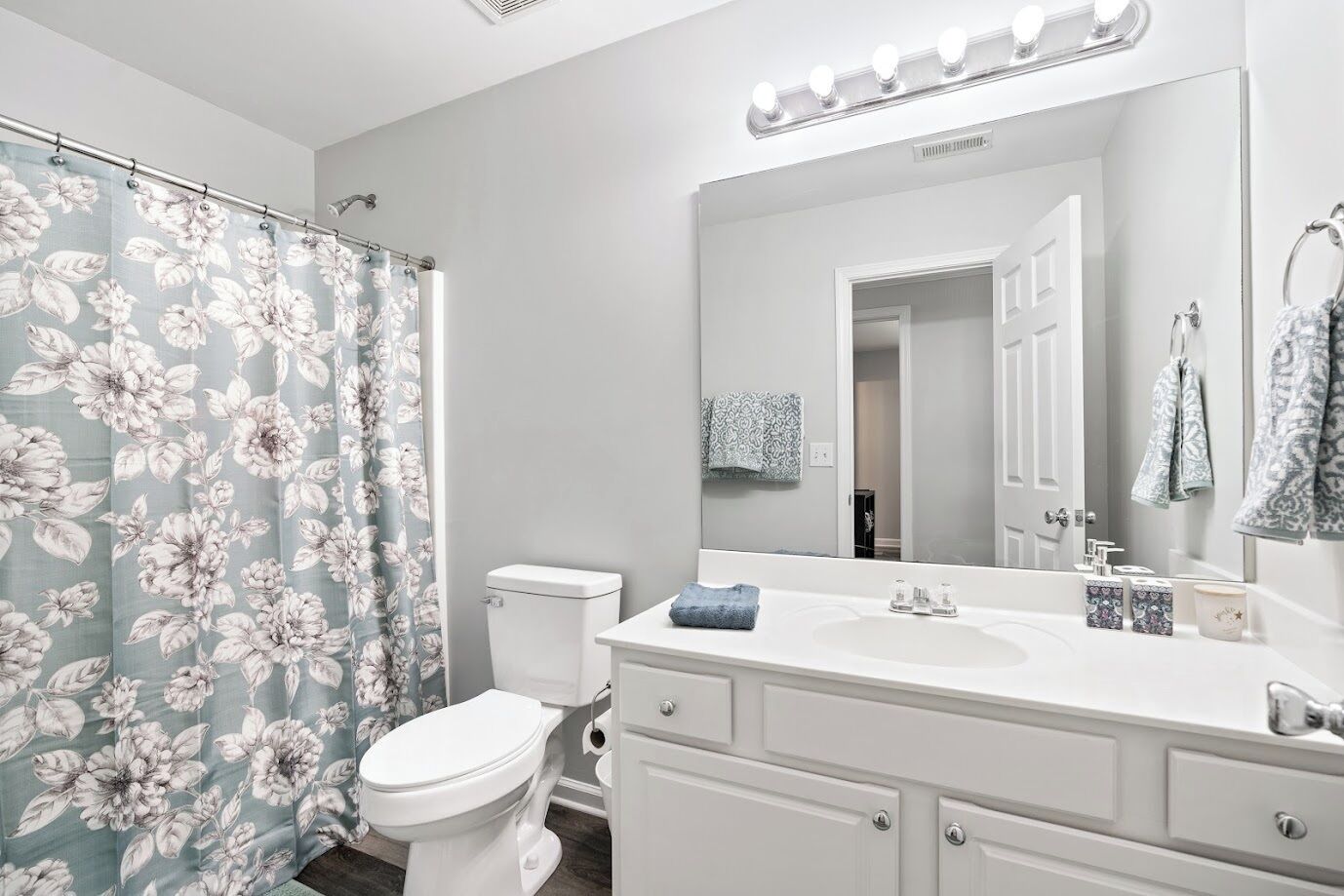 A bathroom with a toilet, sink, and mirror.