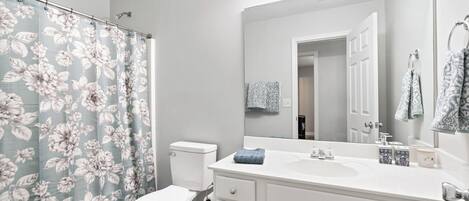 A bathroom with a toilet, sink, and mirror.