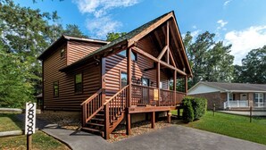 A log cabin with a porch and a staircase leading to the entrance.