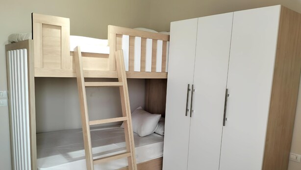 A bunk bed with a ladder, a wardrobe, and a bedside table.