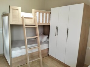 Una cama litera con escalera, un armario y una mesita de noche.