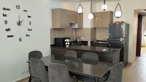 A modern kitchen with a central island, grey chairs, and pendant lighting.