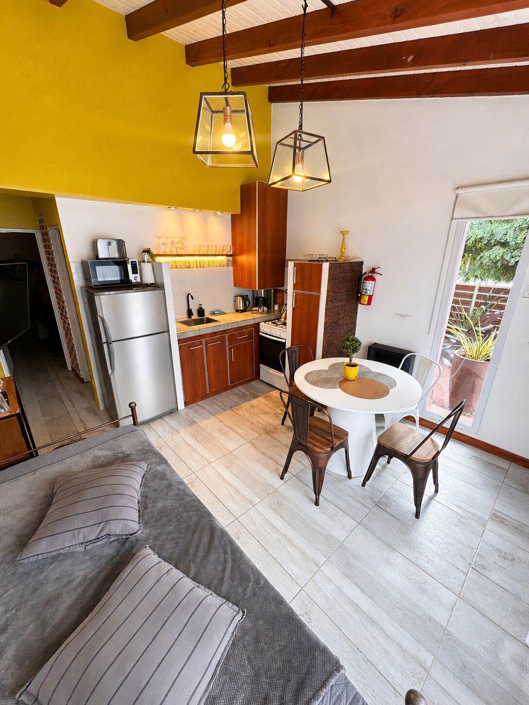 Una cocina compacta con electrodomésticos modernos, un comedor con mesa redonda y una zona de estar acogedora con sofá.