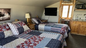 A bedroom with two beds, a wooden cabinet, a television, and a window.