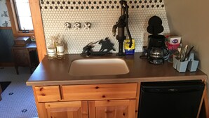 A kitchen with a wooden countertop, a sink, a coffee maker, and a dishwasher.