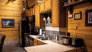 A kitchen with wooden cabinets, a stove, a sink, and a toaster. - The Snow Goose Lodge (Jamestown)