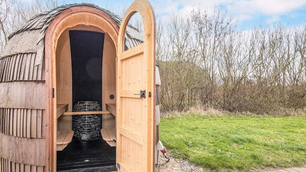 Een sauna met een houten gevel en een grote, rondbogen-ingang.