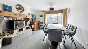 Un comedor con una mesa grande y sillas, una chimenea y un ventanal con cortinas.