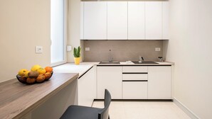 A compact kitchen with white cabinets, a wooden countertop, and a black chair. - Elegant, New, Spacious 3Bedroom Home Between Vatican, Piazza Navona & Trastevere (Roma)