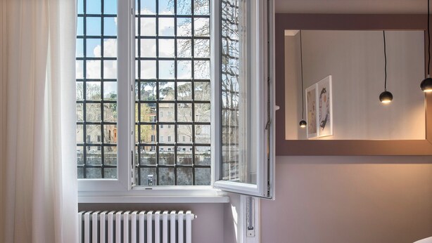 A bedroom with a large window, a radiator, a bed, and two pendant lights. - Elegant, New, Spacious 3Bedroom Home Between Vatican, Piazza Navona & Trastevere (Roma)