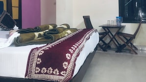 A hotel room with a bed, a small table, and a window. - Hotel Darpan Palace (New Delhi)