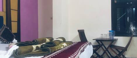 A hotel room with a bed, a small table, and a window.