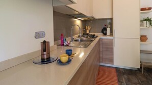 A modern kitchen with a built-in stove, sink, and a wooden countertop. - Turati Family Apartment | Balcone e posto auto (Lecco)