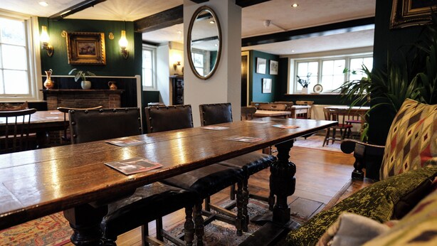 A dining area with a long wooden table, several chairs, and a large mirror on the wall. - Royal Oak Retreat - Sleeps 6, Pub & Pet Friendly (Lewes)