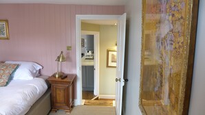 A bedroom with a bed, bedside table, lamp, and a door leading to a bathroom. - Royal Oak Retreat - Sleeps 6, Pub & Pet Friendly (Lewes)