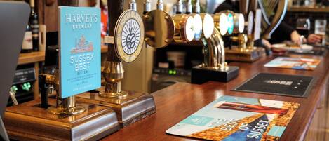 A bar with multiple beer taps, a sign for 'Harvey's Brewery Sussex Best Bitter', and a menu board.