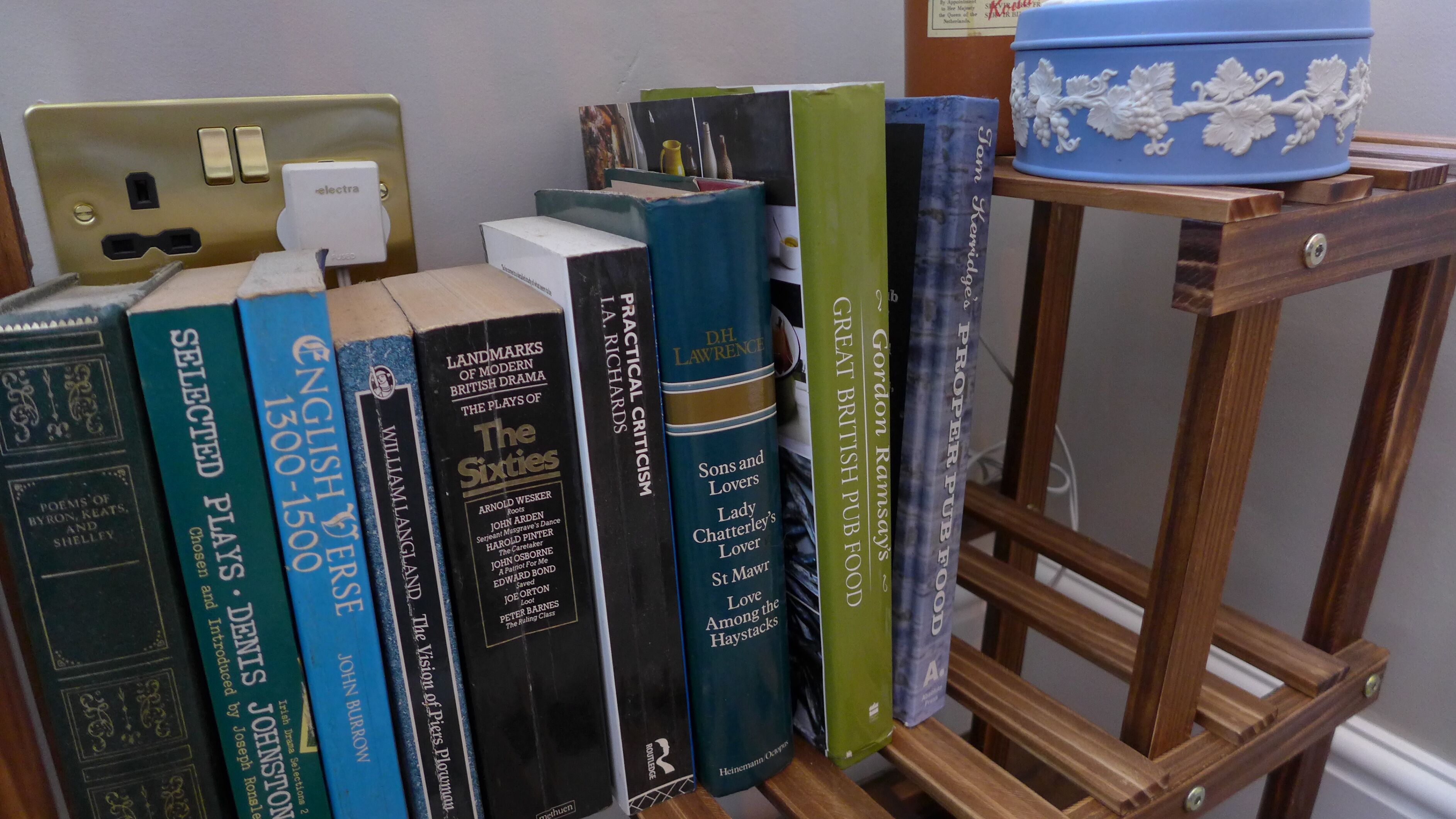 Ein Bücherregal mit verschiedenen Büchern, einem blauen Dekorationsbehälter und einer Steckdose.