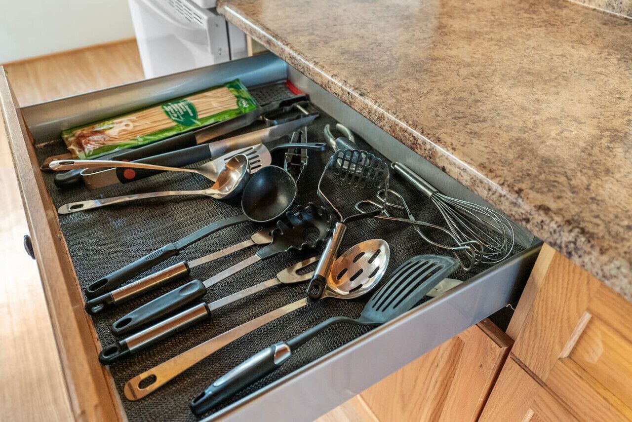 Eine Küchenschublade mit verschiedenen Utensilien und einer Packung Holzstäbchen.