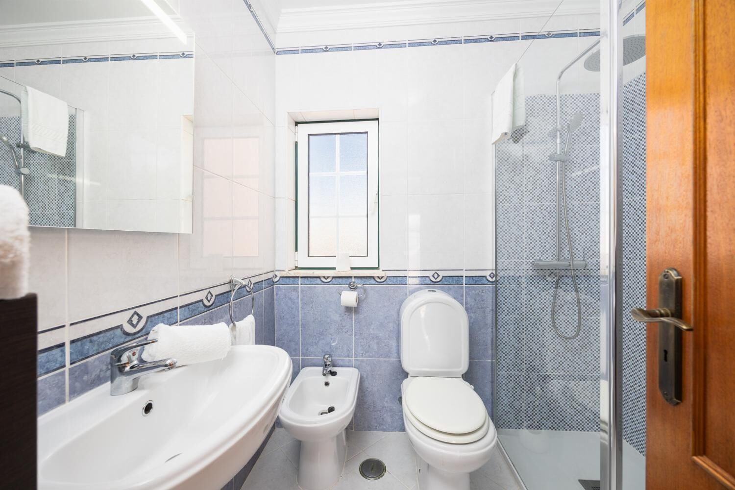 A modern bathroom with a sink, bidet, toilet, and shower.