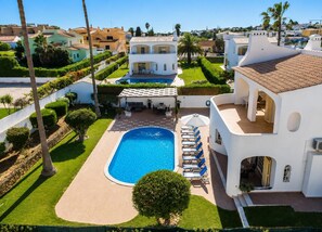 A residential property with a swimming pool, lounge chairs, and a well-maintained garden.