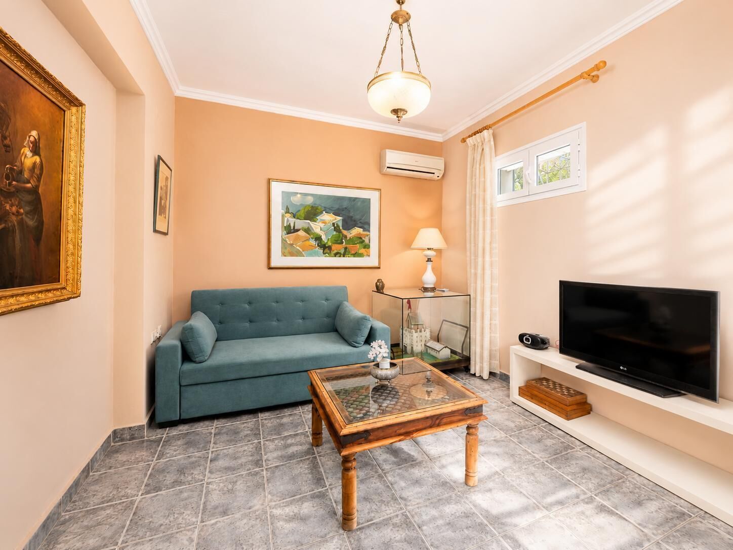 Un salon avec un canapé, une table basse, un téléviseur et un tableau accroché au mur.