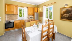 A compact kitchen with wooden cabinets, a microwave, and a dining area set for four with a table and chairs.