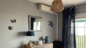 Ein Schlafzimmer mit Bett, Schminktisch, Spiegel und Fenster mit Vorhängen.