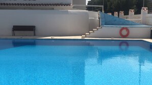 Ein klares, blaues Schwimmbecken mit Stufen, die zu einem weißen Gebäude führen.