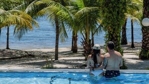 A pool area with a view of the sea, surrounded by palm trees and a sandy beach. - Eden do Catu - BRAGA um paraiso privado a Beira da Lagoa  (Tapera)