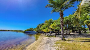 A beach with clear water, palm trees, and a boat. - Eden do Catu - BRAGA um paraiso privado a Beira da Lagoa  (Tapera)