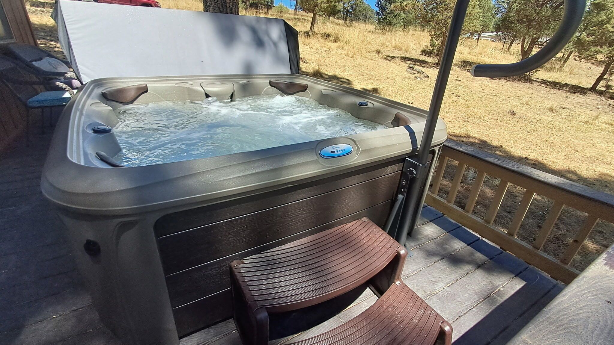 Un bain à remous doté d’un panneau de commande, d’une terrasse en bois et d’une chaise.