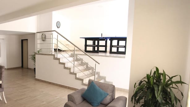 A modern living room with a staircase, a sofa, a coffee table, and a large plant. - CASA LAURELES ESTADIO MEDELLIN (Medellín)