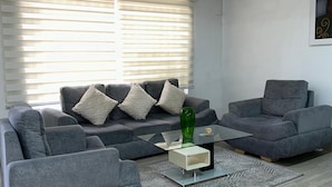 A modern living room with grey sofas, a glass coffee table, and a patterned rug. - CASA LAURELES ESTADIO MEDELLIN (Medellín)