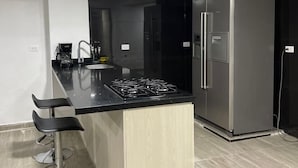 A modern kitchen with a black countertop, stainless steel appliances, and a wooden cabinet. - CASA LAURELES ESTADIO MEDELLIN (Medellín)