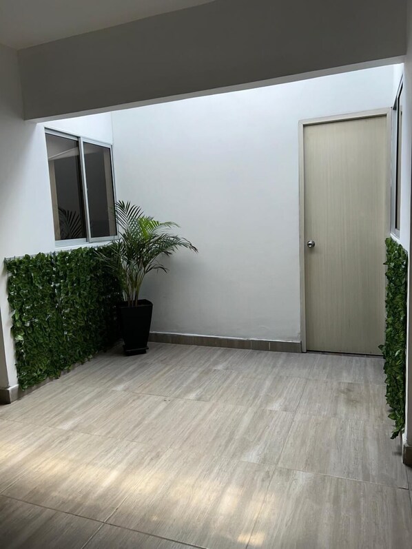 Un couloir propre et moderne, avec un plancher de couleur claire, une porte et une fenêtre équipée de stores.